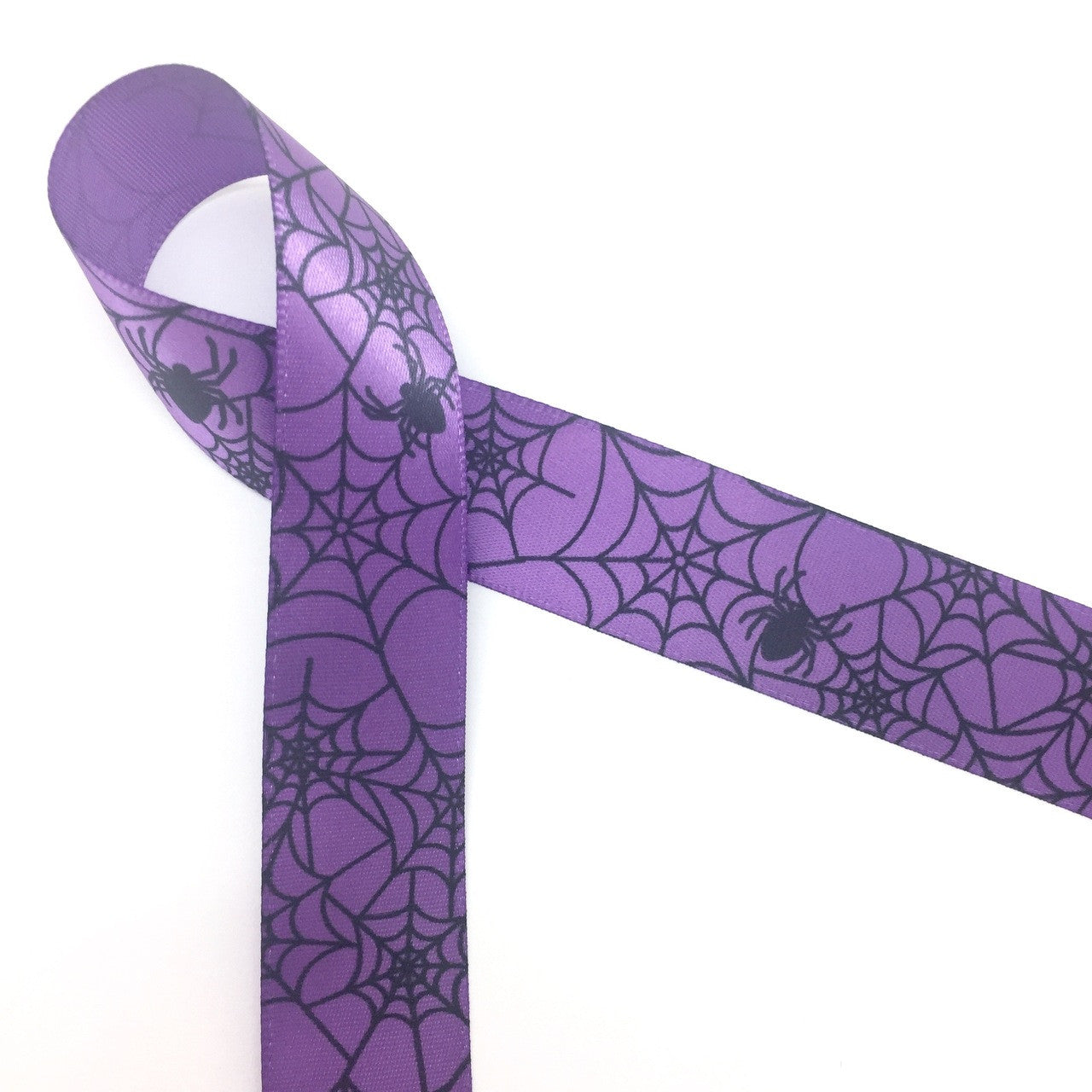 Spider webs and spiders in black printed on 7/8" purple single face satin ribbon is on trend for those who love a traditional Halloween! This ribbon is more sweet than spooky and is ideal for the younger set's Halloween party decor, party favors, gift wrap, treat bags, cookies and cake pops. This is a great ribbon for hair bows, head bands fascinators, sewing and quilting projects too. All our ribbon is designed and printed in the USA