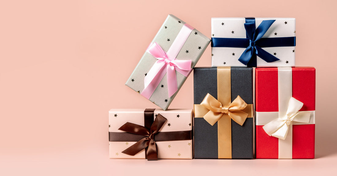 A stack of five different colored and patterned gifts. Each are lying in a different orientation and show case ribbon bows.