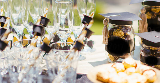 A close-up of a graduation party table. There are jars with graduation caps and various glasses set up on the table.