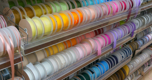 A store display of several different types and colors of ribbon. They are organized by color and type.