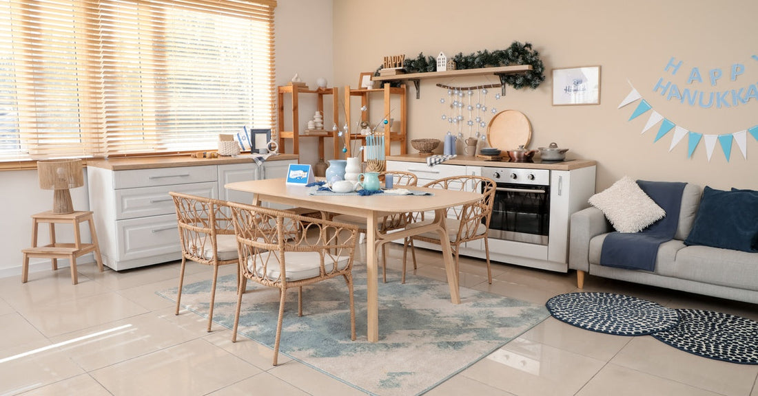 A bright kitchen with various Hanukkah decor. The dining table has blue jars, and a bunting banner hangs on the wall.