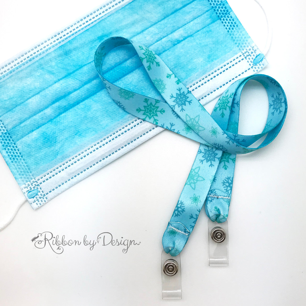 Attach our Frozen blue snowflake design mask holder by  opening the snaps and securing the loops of the mask to the lanyard! Never have a lost face mask on the playground, in school, at sports practice or in dance class again!