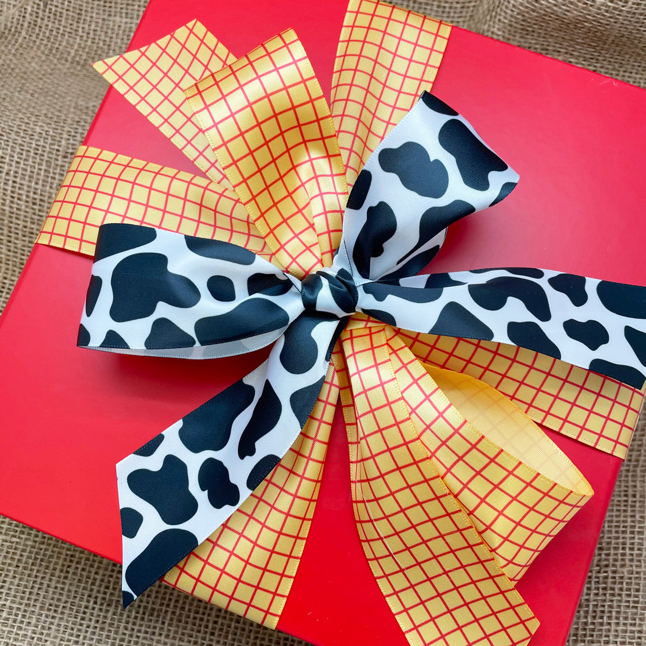 Our cow print ribbon paired with  our red and yellow plaid makes for the perfect Toy Story  themed  gift wrap!