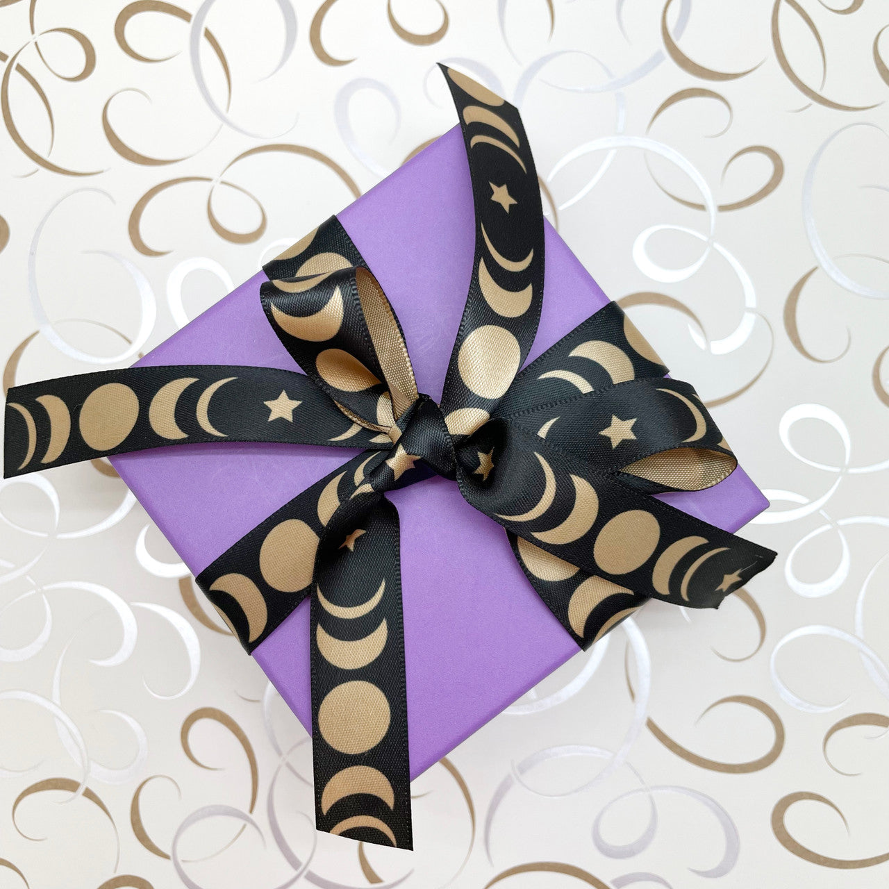 Moon phase ribbon tied on a purple package makes for a pretty gift for any celestial  themed celebration!