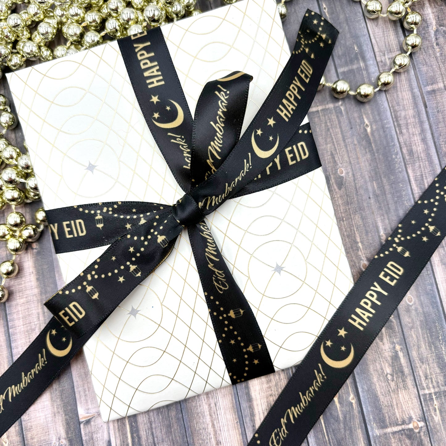 Happy Eid, Eid Mubarak ribbon in gold with a crescent moon and lanterns on a black background printed on 5/8" dijon gold satin