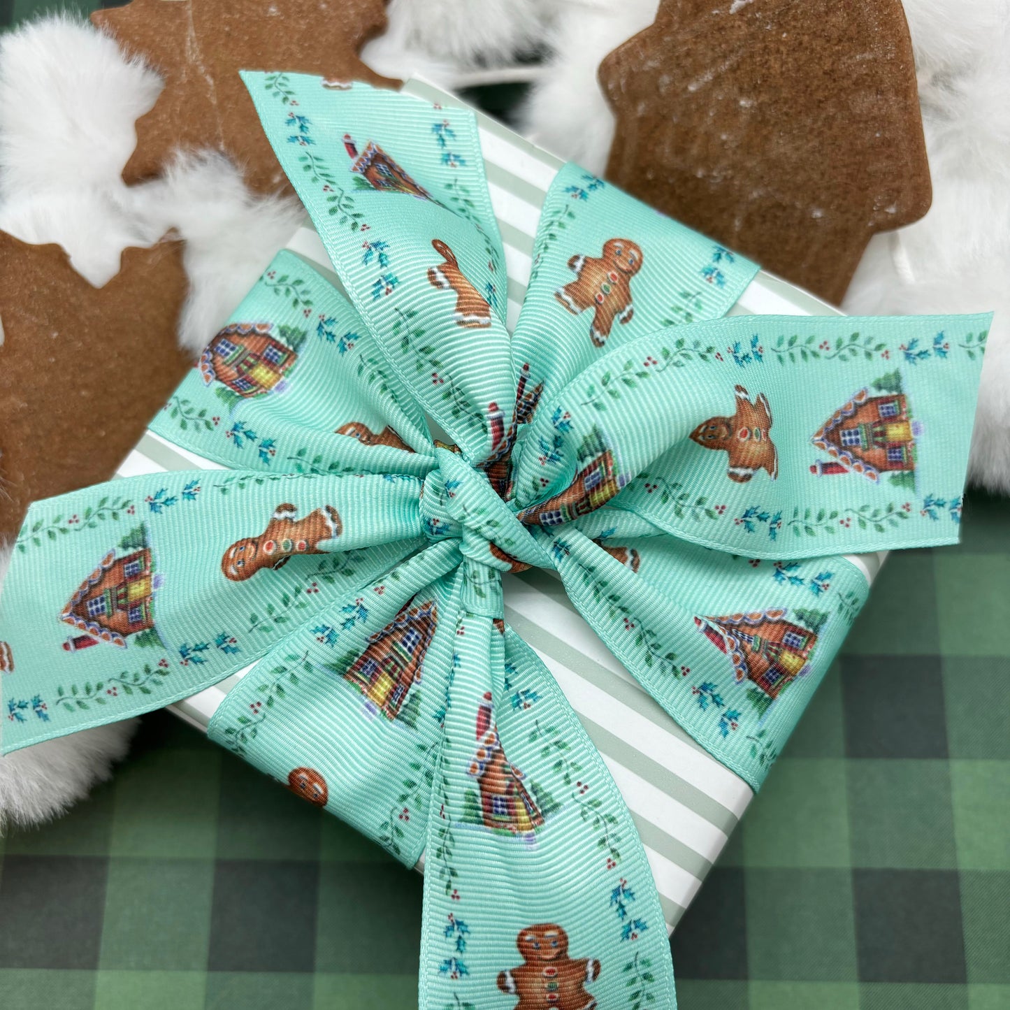 Holiday Cookie ribbon gingerbread men and houses with a holly border on a blue green background printed on 1.5" white grosgrain