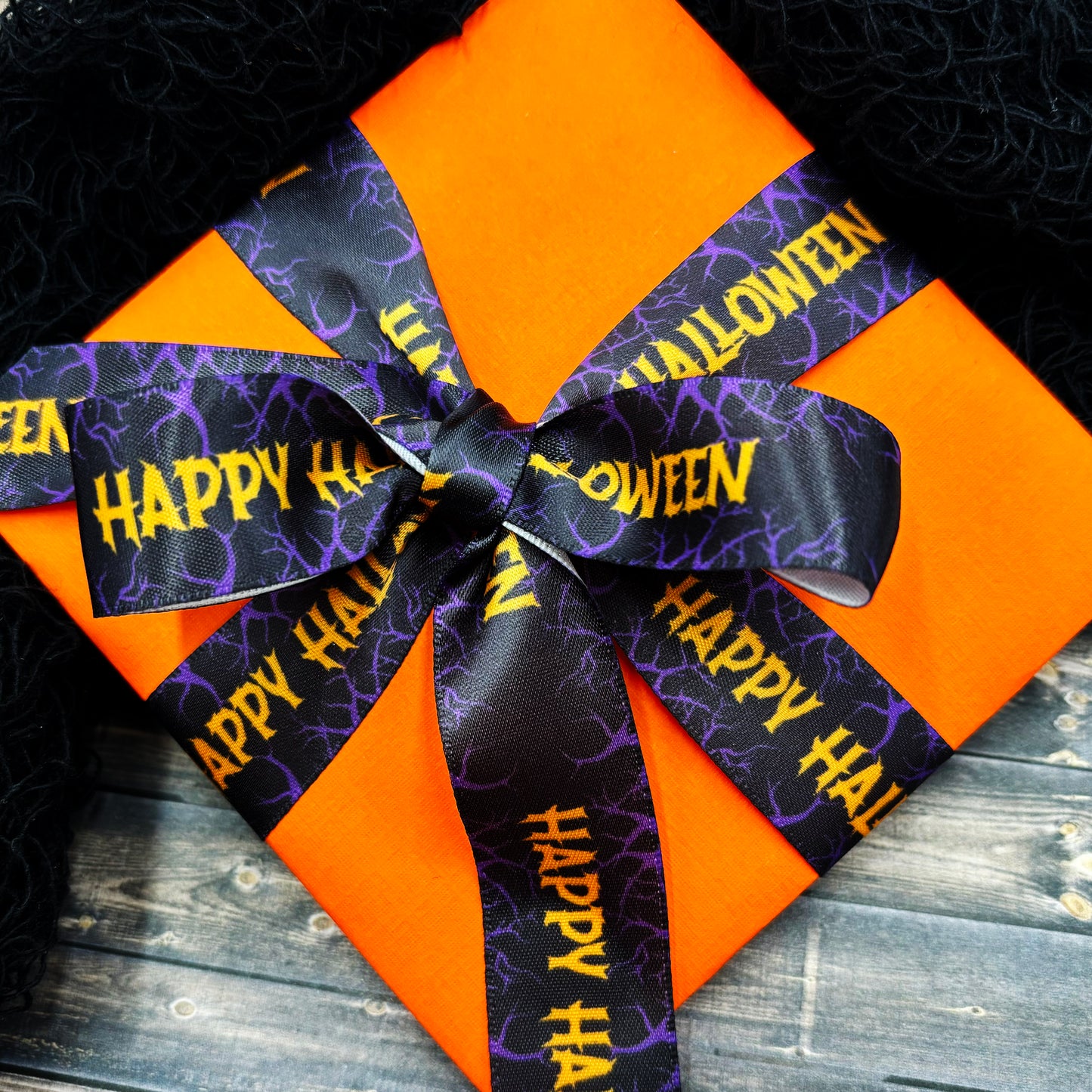 Happy Halloween Ribbon featuring Happy Halloween in orange on a black background with purple branches printed on 7/8" white satin