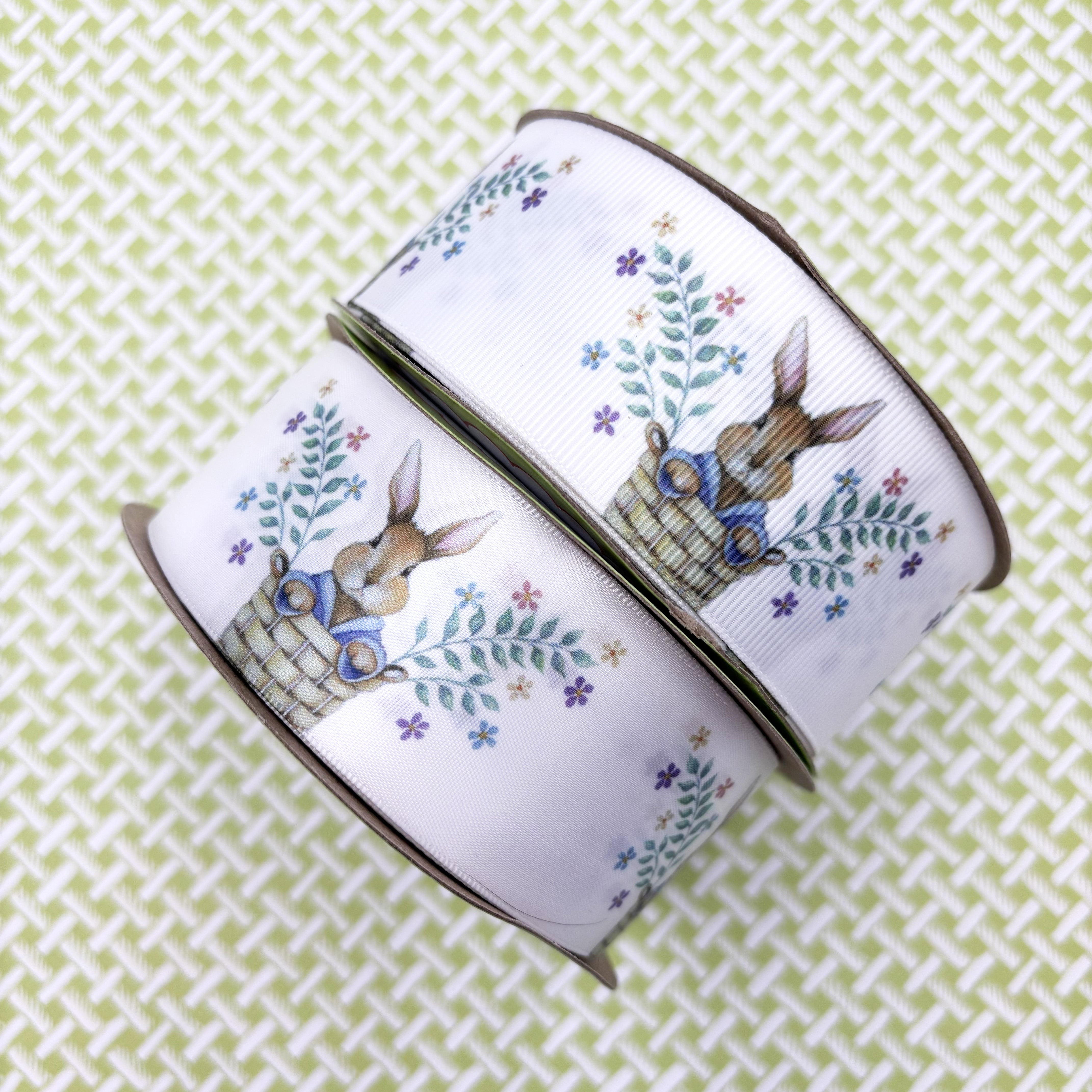 Bunny ribbon Easter bunny pops out of a basket with sprigs of Spring f