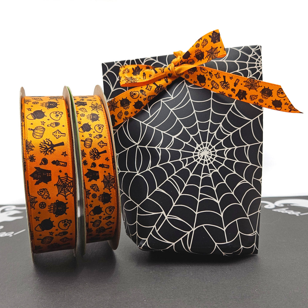 Halloween Ribbon tossed elements of skulls, haunted houses, cauldrons, scary trees and more in black printed on 5/8" and 7/8" tangerine single face satin