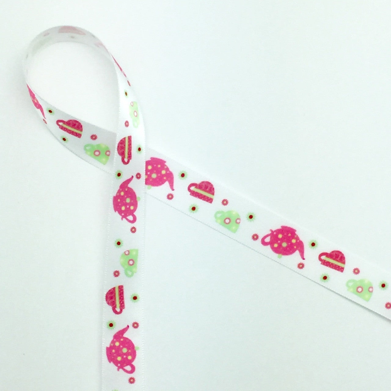 Tea pots and tea cups are featured  in pink and green on a 5/8" white single face satin ribbon. Treat Mom to some spiced tea and cookies tied with this sweet ribbon to capture her heart on Mother's Day!