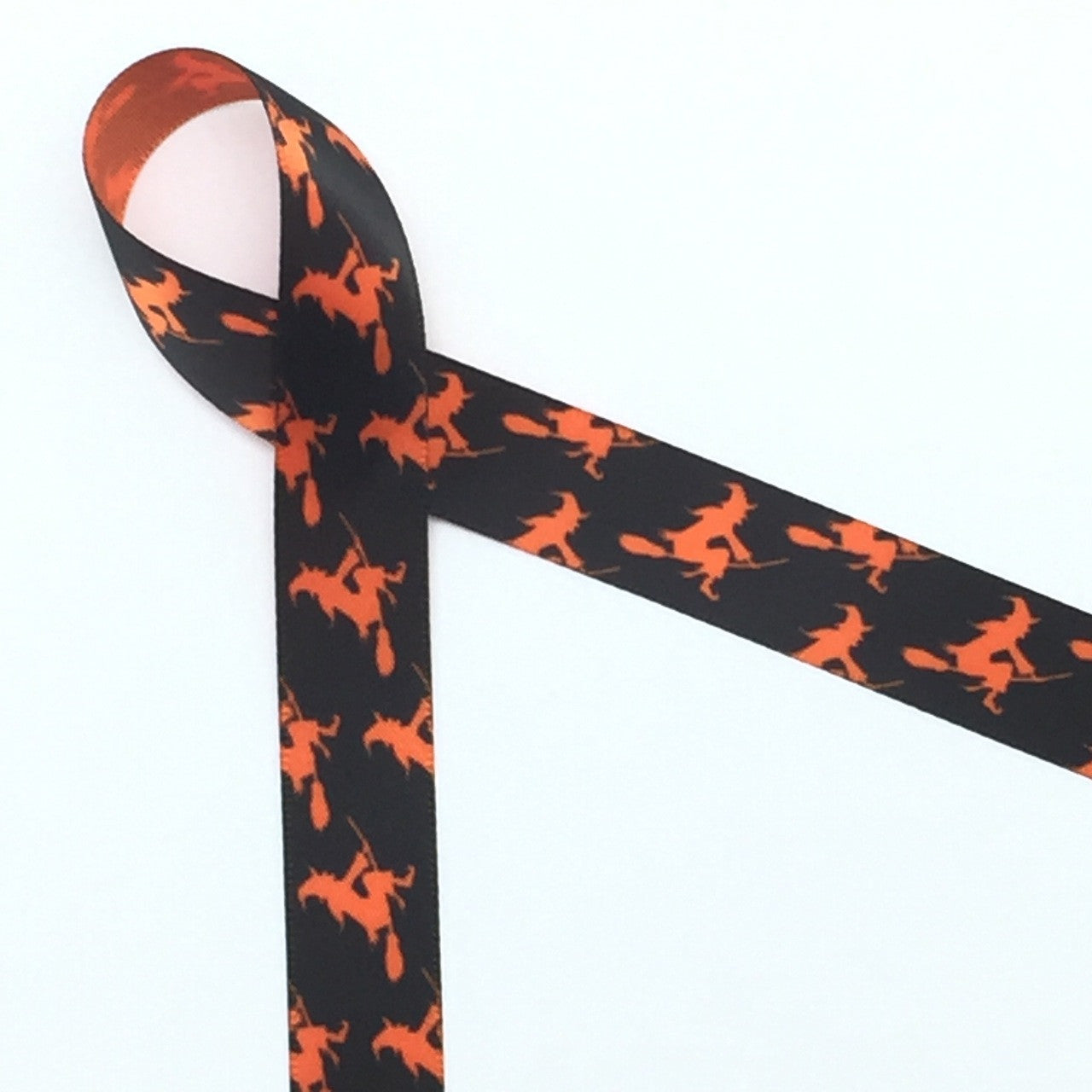 Witches flying on their brooms in silhouette are the perfect addition to your Halloween Treats. This ribbon is 5/8" wide printed  on torrid orange single face satin
