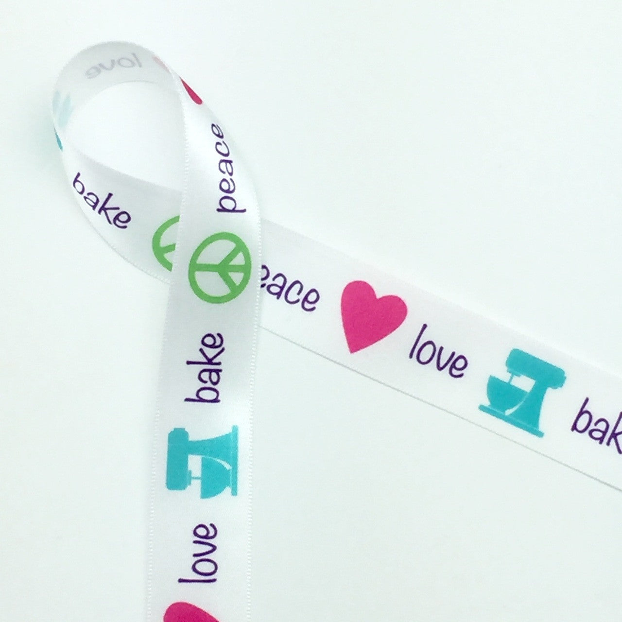 Peace, Love, Bake in purple lettering with a lime peace symbol, pink heart and teal mixer on 7/8" White single face satin ribbon, 10 yards