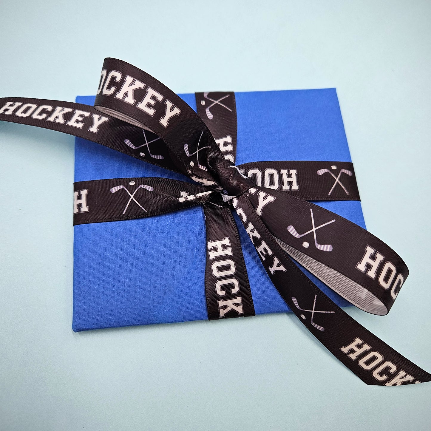 Hockey Ribbon with crossed Hockey sticks in white on a black background printed on 5/8" and 7/8" white satin