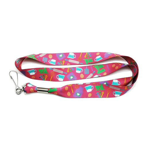 A fun lanyard featuring baking elements tossed on a bright pink background. A great way to keep keys visible while celebrating your love of baking!